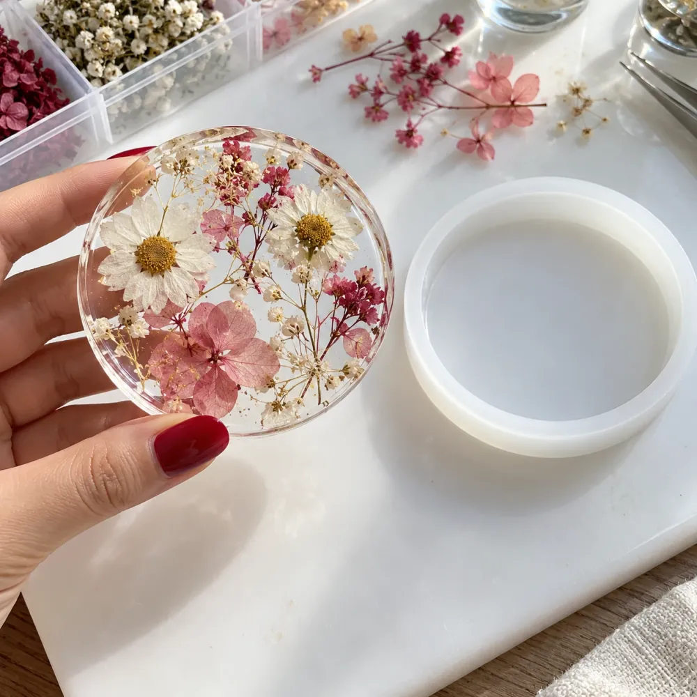 Posavasos de resina epoxi con flores secas recién desmoldado junto al molde de silicona